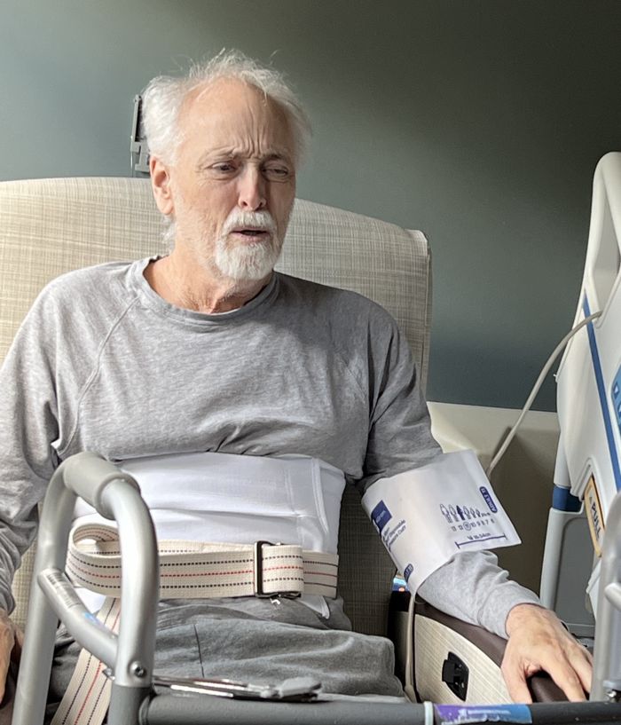 Brian in a hospital chair with his walker